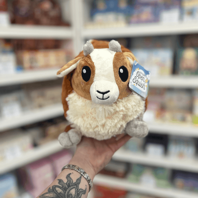 Mini Squishable Baby Goat plush toy held in hand, front view showing the sweet goat face, soft brown and cream plush fur, tiny grey horns and fluffy chest