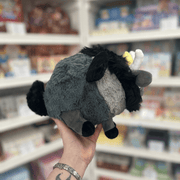 Mini Squishable Baphomet plush toy held in hand, rear angled view showing the grey plush body, black tail, black mane and folded black wings
