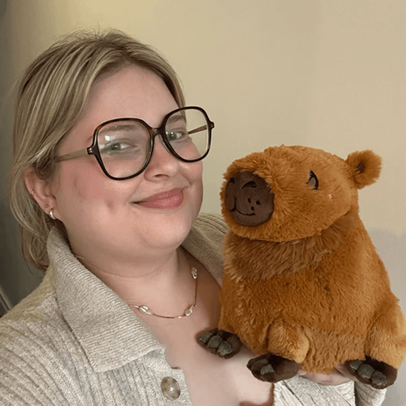 Person holding a Mini Squishable Capybara plush toy to show its size and soft, fluffy texture