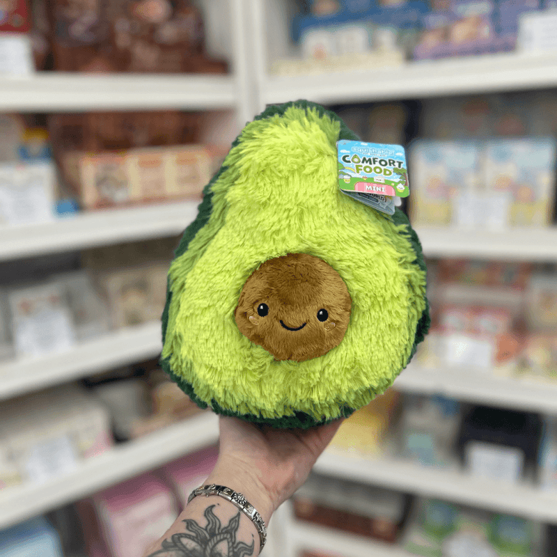 Mini Squishable Comfort Food Avocado plush toy held in hand, front view with smiling avocado stone detail