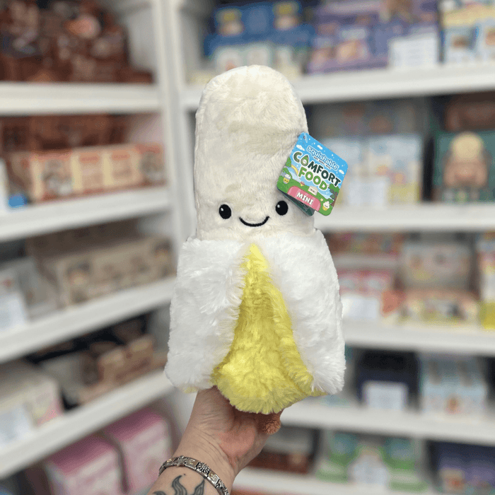 Mini Squishable Comfort Food Banana plush toy held in hand, front view showing the smiling peeled banana design