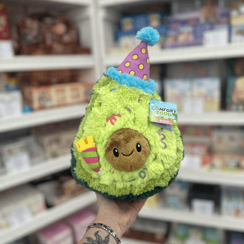 Mini Squishable Comfort Food Birthday Avocado plush toy held in hand, front view with party hat and candle