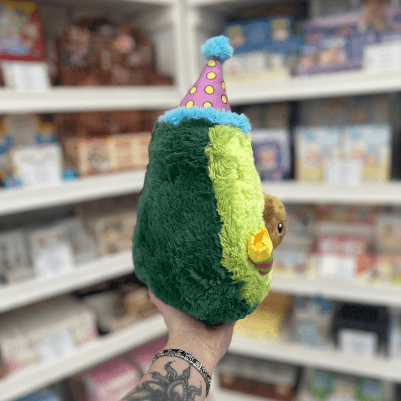 Mini Squishable Comfort Food Birthday Avocado plush toy held in hand, side view showing plush avocado shape