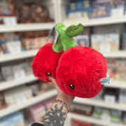 Mini Squishable Comfort Food Cherries plush toy held in hand, angled view showing the pair of red cherries with embroidered faces and green leaf detail