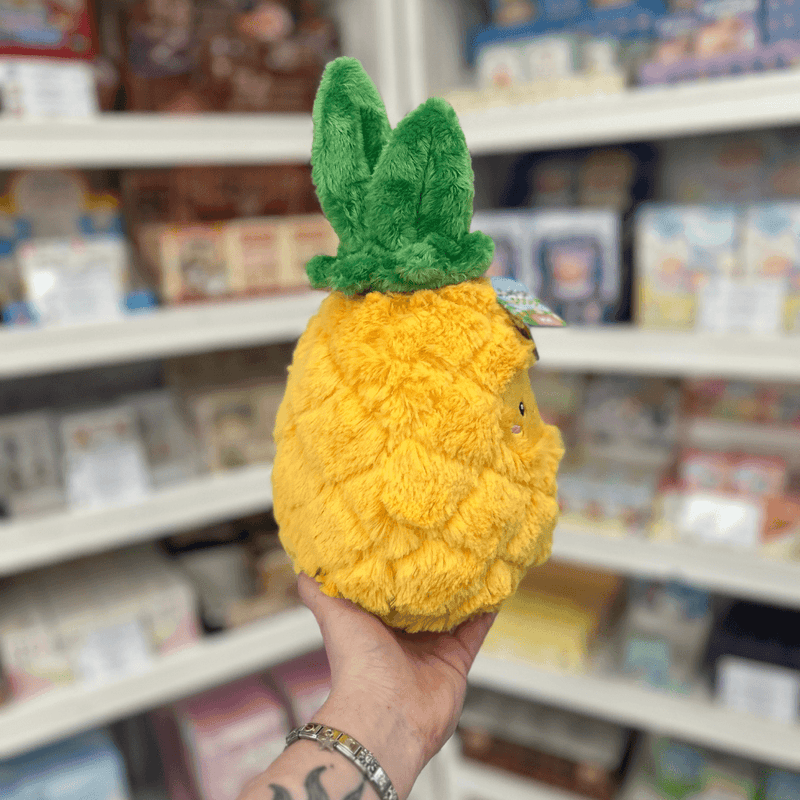 Mini Squishable Comfort Food Pineapple plush toy held in hand, side view showing the fluffy pineapple texture and soft green leaf crown