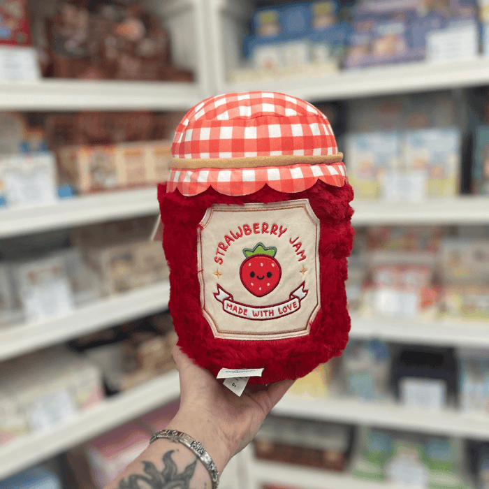 Mini Squishable Comfort Food Strawberry Jam plush toy held in hand, back view showing the embroidered strawberry jam label and red plush sides