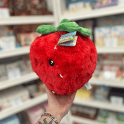Mini Squishable Comfort Food Strawberry plush toy held in hand, angled view showing the cheerful face, plush strawberry shape and soft green leaf detail