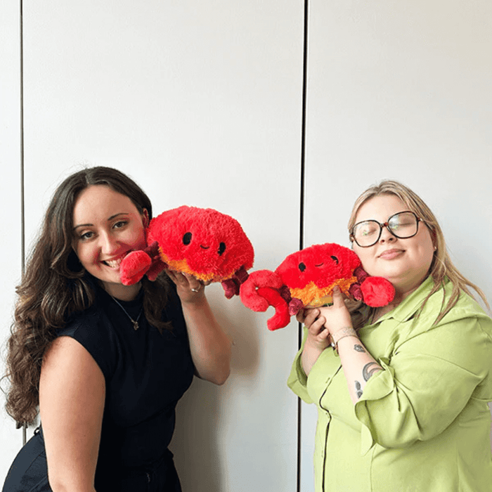 Two people holding bright red Mini Squishable Crab plush toys