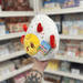 Mini Squishable Deviled Egg plush toy held in hand, angled side view showing yellow devilled centre, red horns and side wing detail