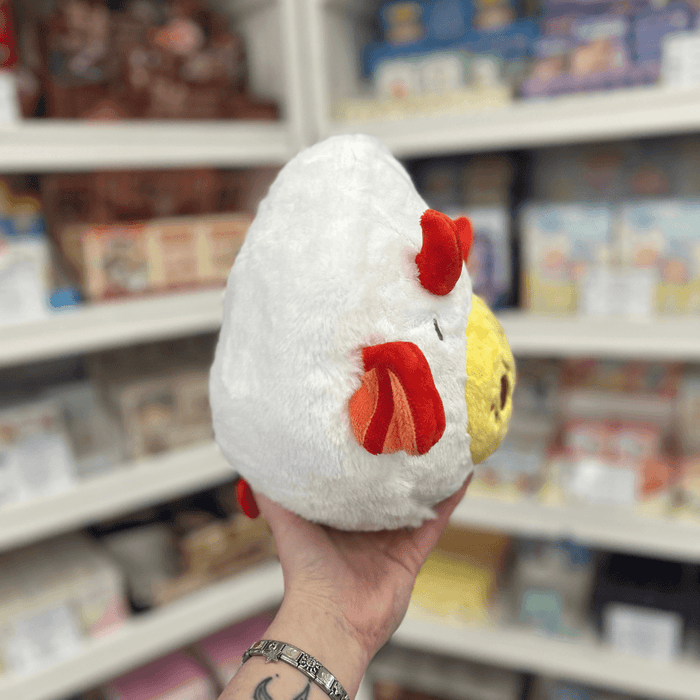 Mini Squishable Deviled Egg plush toy held in hand, side view showing white plush body, red horn and devil wing detail