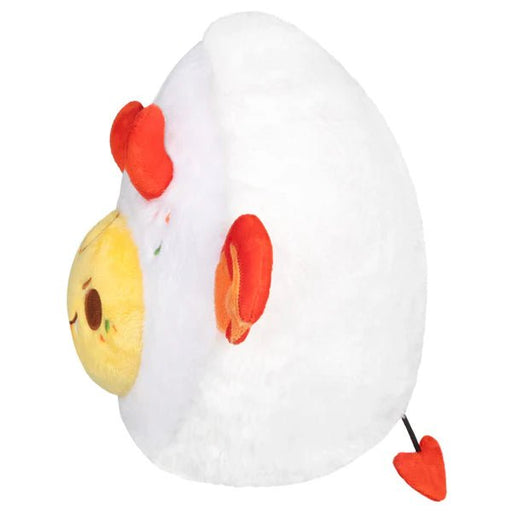 Side view of Mini Squishable Deviled Egg plush showing yellow yolk face and orange bat wing