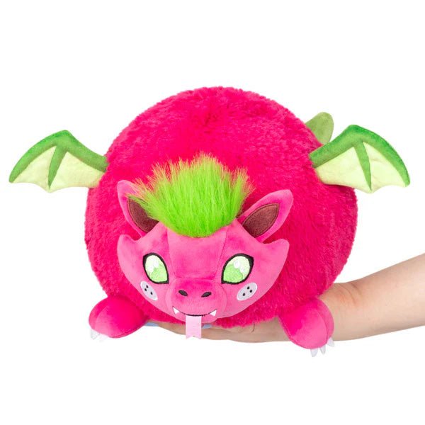 Front view of the Mini Squishable Dragon Fruit plushie featuring a vibrant pink dragon with green wings and fuzzy green hair.