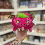 Mini Squishable Dragon Fruit plush toy held in hand, front view showing the bright pink dragon face, green tuft, little wings and dragon fruit-inspired body