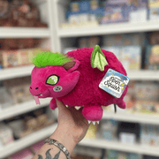 Mini Squishable Dragon Fruit plush toy held in hand, angled side view showing the pink dragon face, green wings, small horns and fluffy dragon fruit body