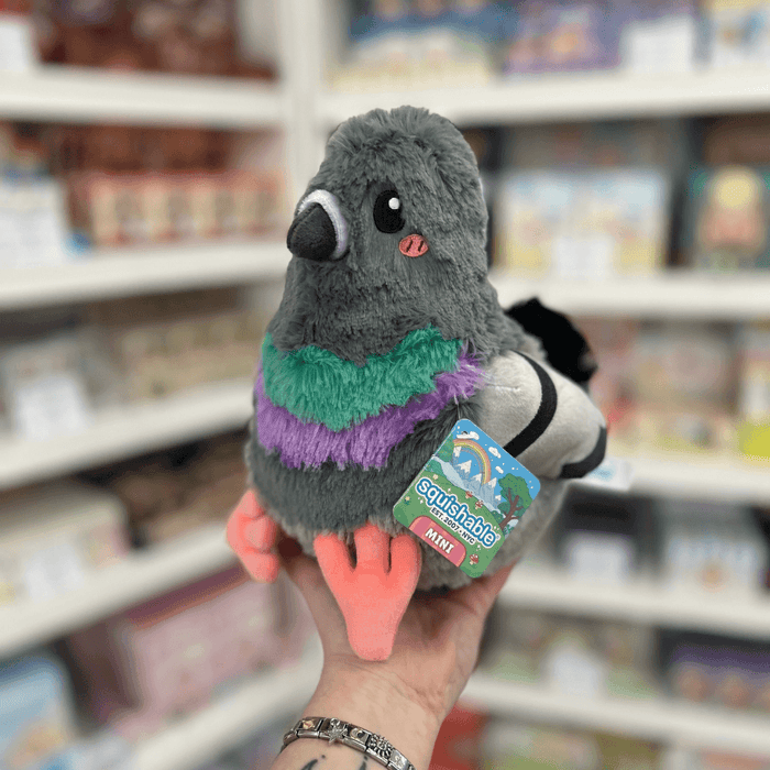 Mini Squishable Pigeon plush toy held in hand with tag visible