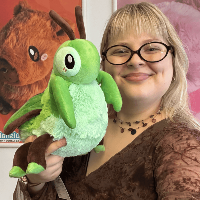 Person holding Mini Squishable Praying Mantis plush showing its bright green body and curved front legs
