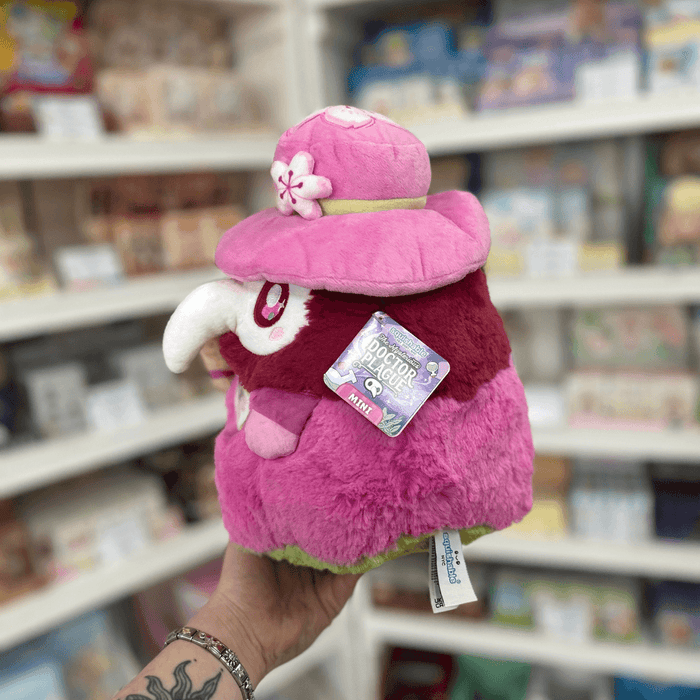 Side view of Mini Squishable Sakura Plague Doctor plushie with pink hat, white beak mask and official Squishable tag