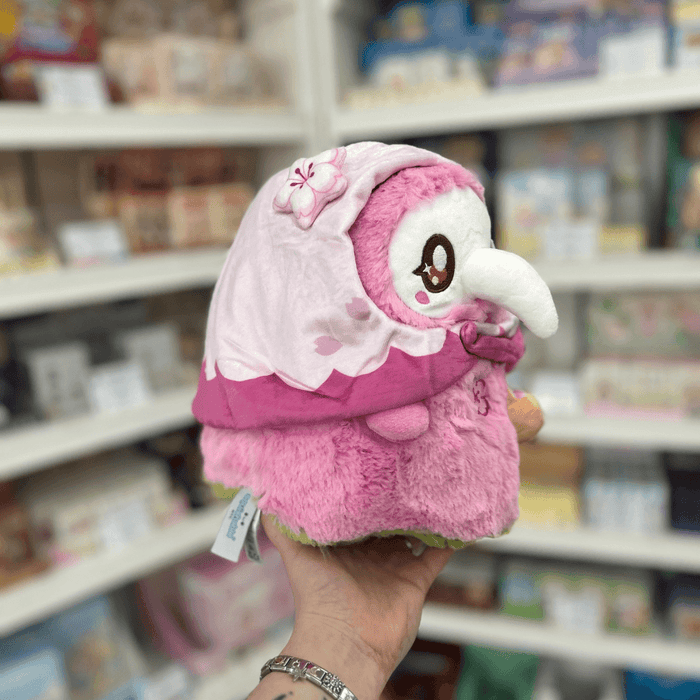 Mini Squishable Sakura Plague Nurse pink plushie side view with cherry blossom hood, soft fluffy body and cute plague mask