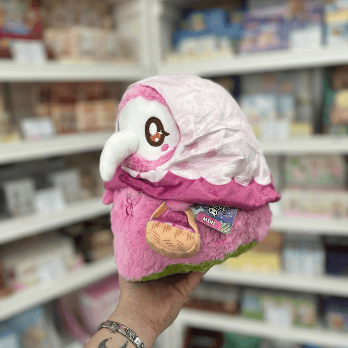 Side view of Mini Squishable Sakura Plague Nurse plushie showing its white beak mask, pink cloak and official Squishable tag