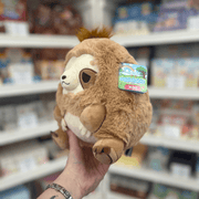 Mini Squishable Sleepy Sloth plush toy held in hand, angled side view showing the fluffy brown fur, rounded body, cream face and Squishable tag