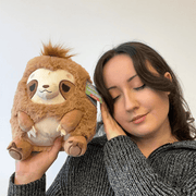 Person holding Mini Squishable Sleepy Sloth plush toy next to their face.
