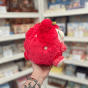 Mini Squishable Strawbeary plush toy held in hand, back and side view showing the rounded red plush shape, strawberry seed details and small ears