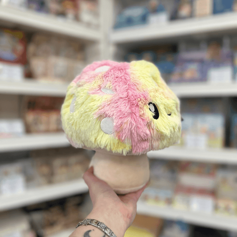 Mini Squishable Tie Dye Mushroom plush toy side view held in hand in a shop
