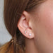 Close-up of silver moon and star crystal stud earrings worn on ear