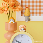 Mofusand shrimp cat figures peeking over a desk clock