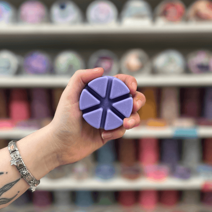 Moonlit Forest wax melt segments held in hand with colourful wax melt display in the background