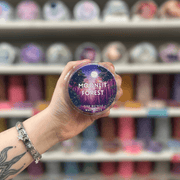 Moonlit Forest wax melt pot held in hand with colourful wax melt display in the background