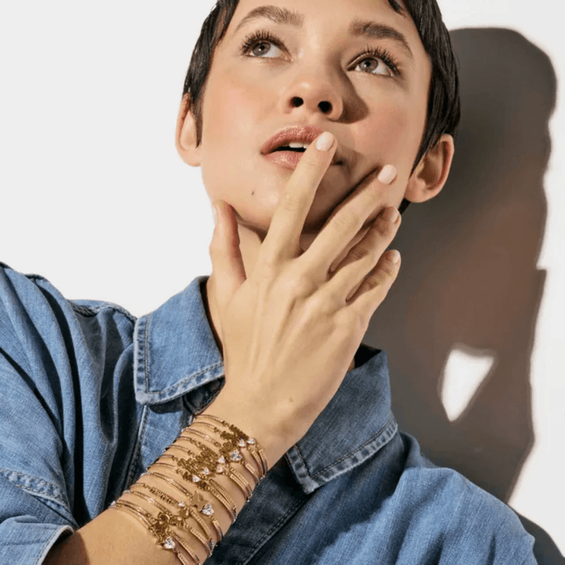 Model wearing stacked Nomination Milleluci bracelets including the rose gold-tone four leaf clover design