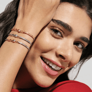 Model wearing stacked Nomination Milleluci adjustable bracelets including the yellow gold-tone LOVE design