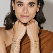 Front view of model with both wrists stacked in Nomination Milleluci Bracelets; star motif bracelet shown with adjustable slider chain.