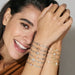 Model smiling while wearing stacked Nomination Milleluci Bracelets, including the yellow-gold PVD star bracelet with Cubic Zirconia.