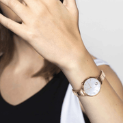 Model wearing a gold-tone Nomination watch with a pale round dial and cubic zirconia detail.