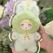 Avocado Nommi – mint‑green bunny suit, yolk‑yellow tummy and stitched avocado pit badge.
