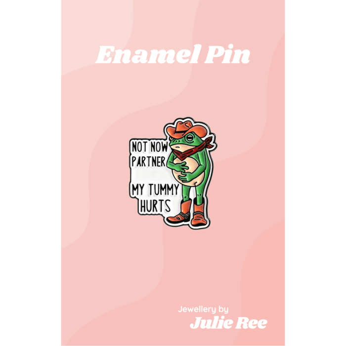 Funny enamel pin of a green cowboy frog with the quote Not now partner my tummy hurts