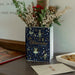 Navy Nutcracker book vase on shelf with festive sprigs and biscuits