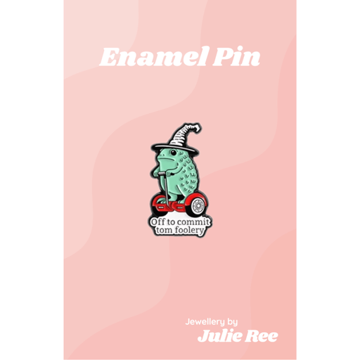 Funny enamel pin of a frog in a witch hat riding a scooter with the words Off to commit tom foolery
