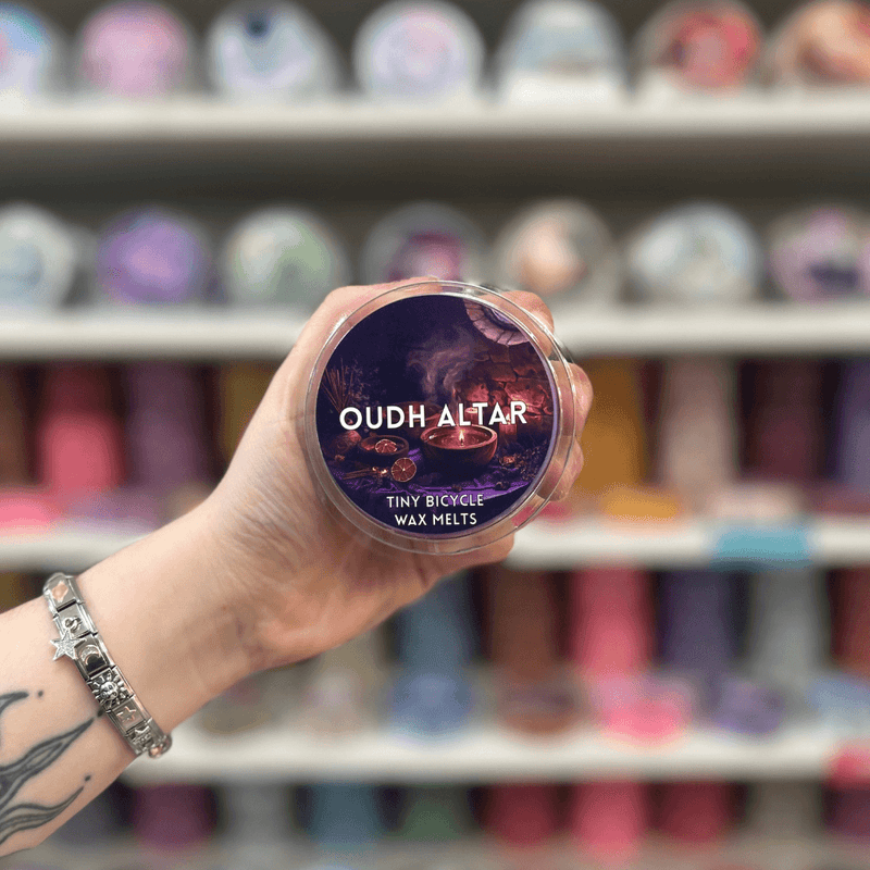 Oudh Altar wax melt pot held in hand with colourful wax melt display in the background
