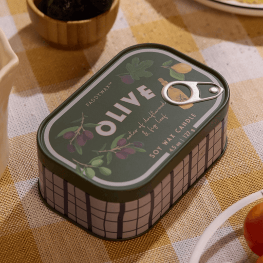 Paddywax Bistro Fig and Olive tin candle on a checked tablecloth with olives and bistro table setting