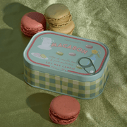 Paddywax Bistro Macaron tin candle displayed with colourful macarons