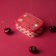 Paddywax Bistro Smoked Cherry tin candle displayed with fresh cherries
