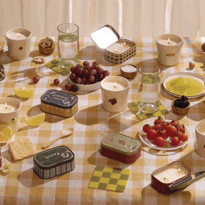 Paddywax Bistro tin candle collection displayed on a café-style table with food and candles