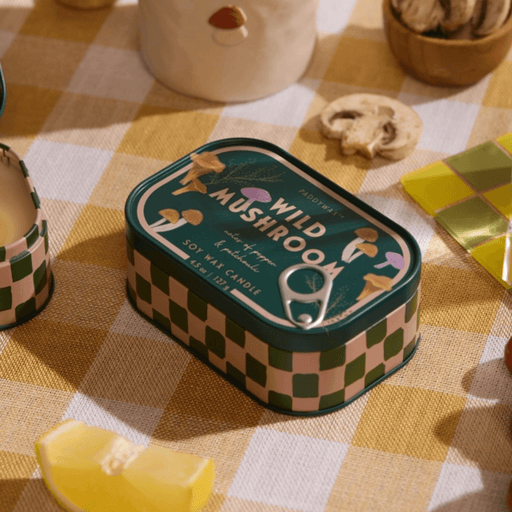 Paddywax Bistro Wild Mushroom tin candle on a checked tablecloth with mushrooms and lemon
