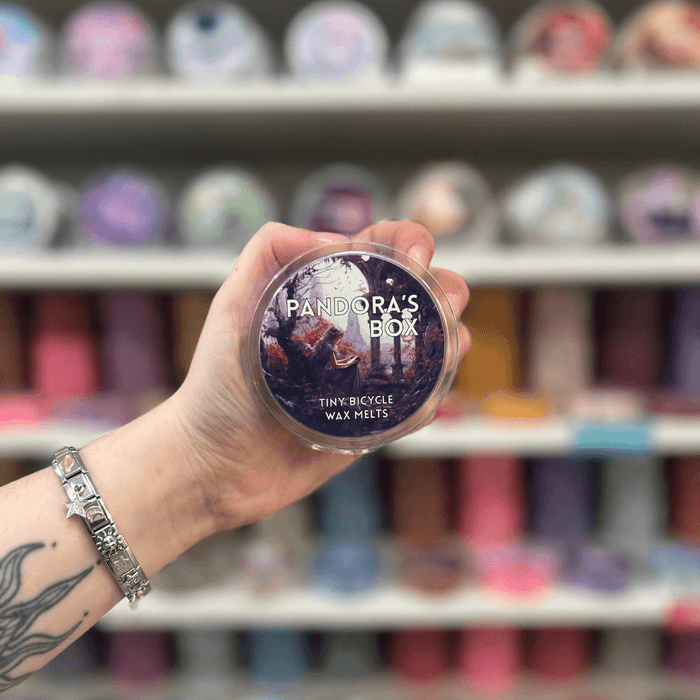 Pandora's Box wax melt pot held in hand with colourful wax melt display in the background