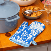 Blue Q Party’s In The Kitchen oven mitt on a countertop beside food and wine