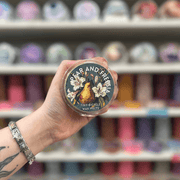 Pear and Freesia wax melt pot held in hand with colourful wax melt display in the background