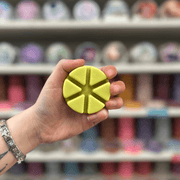 Pear and Freesia wax melt segments held in hand with colourful wax melt display in the background